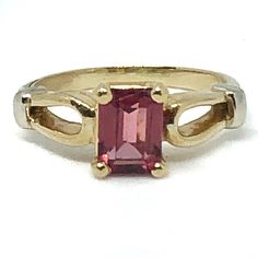 Gorgeous 14K gold and rhodolite garnet ring would make the most thoughtful and beautiful gift for someone special!  It would also be an enchanting engagement ring, with its shimmering pinkish red rosé wine colored solitaire emerald-cut stone. Shimmery & clear deep rose pink pyrope garnet, known as a rhodolite garnet, is free of visible inclusions. Finger size is 5-3/4 (could be resized within reason by a reputable jeweler).  Emerald-cut stone is about 5 x 7mm. Beautiful setting is 14 karat yellow gold with white gold shoulder accents. There is even lovely detailing on the shank.  Marked inside "585" (14kt can also be expressed as .585), it weighs 3.4 grams. This ring was purchased new in 1983 & is in wonderful vintage condition. The white heart-shaped ring box shown is NOT included. The te Elegant Tourmaline Solitaire Ring, Elegant Tourmaline Birthstone Ring For Anniversary, Classic Tourmaline Ring With Prong Setting, Elegant Yellow Gold Tourmaline Birthstone Ring, Elegant Tourmaline Promise Ring, Tourmaline Birthstone Ring, Fine Jewelry For Formal Events, Formal Fine Jewelry Tourmaline Birthstone Ring, Elegant Ruby Birthstone Ring With Tourmaline, Tourmaline Birthstone Ring For Formal Occasions