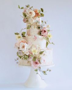 a three tiered wedding cake with pink and white flowers