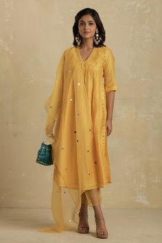 Sunflower yellow kurta highlighted with mirror embroidery, V-neckline, gathers at the yoke and straight silhouette. Comes with scallop edged hem pant and organza dupatta.
Component: 3
Embroidered
Neckline: V-Neck
Sleeve Length: Elbow
Fabric: Kurta: Chanderi; Lining: Cotton; Pant: Cotton, Organza; Dupatta: Organza
Color: Yellow
Sheer organza hem pant
Sequin embellished dupatta
Note: The clutch bag shown in the image is not for sale - Aza Fashions Pant Embroidery, Cotton Palazzo Pants, Yellow Kurta, Mirror Embroidery, Sunflower Yellow, How To Hem Pants, Organza Dupatta, Embroidered Neckline, Indian Fashion Designers