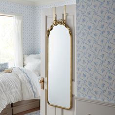 a mirror hanging on the side of a wall next to a bed in a bedroom