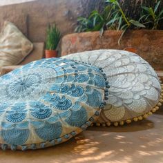 two decorative pillows sitting on top of a table next to a potted plant in a living room