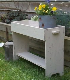 a potted planter sitting on top of a wooden shelf in the grass next to flowers