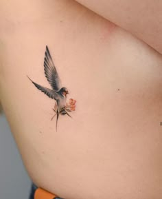 a small bird on the side of a woman's stomach with flowers in it