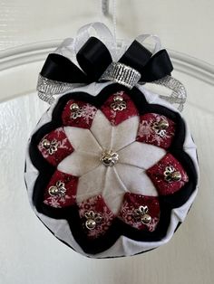 a red and white ornament hanging from a door with black bows on it