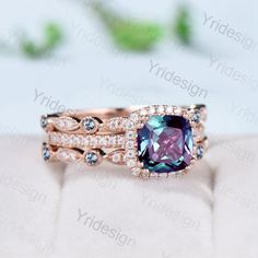 a pink and blue ring set with diamonds on the sides, sitting on top of a white