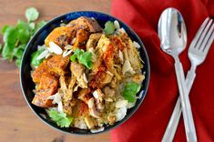 a blue bowl filled with rice and meat next to a fork on top of a red napkin