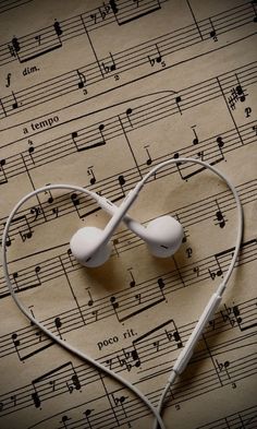 two earphones are placed in the shape of a heart on sheet music with musical notes