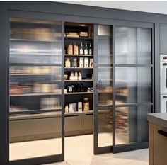 an empty kitchen with stainless steel cabinets and glass doors that open to reveal the pantry