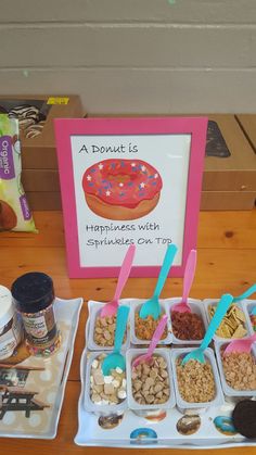 a table topped with trays of food and cups of ice cream next to a sign