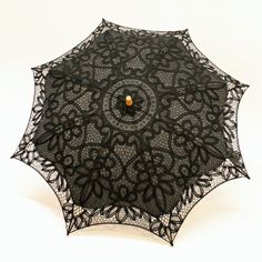 an open black lace umbrella on a white background with a wooden button in the center