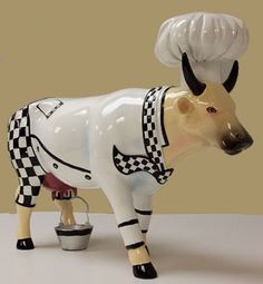 a ceramic cow with a chef's hat and apron on its head is shown