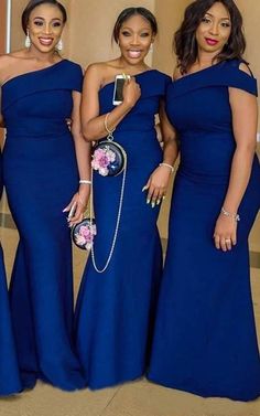 three women in blue dresses posing for the camera with one woman holding a cell phone