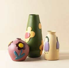 three colorful vases sitting next to each other on a table