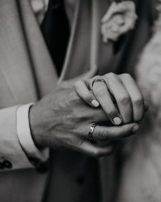 a man and woman holding hands with wedding rings on their fingers in black and white