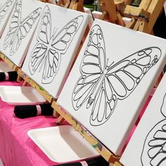 several butterfly paintings are lined up on easels