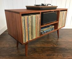 an old record player sitting on top of a wooden cabinet filled with records and vinyl