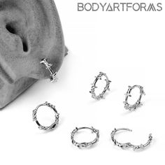 four pairs of silver hoop earrings sitting next to each other