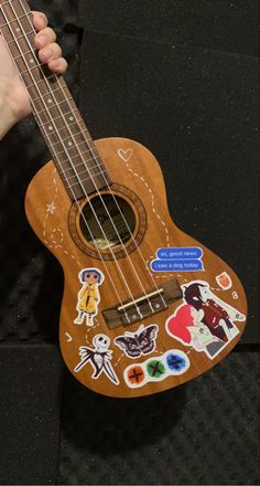 a person holding a ukulele with stickers on it