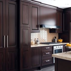 a kitchen with dark wood cabinets and white counter tops is pictured in this image, there are fruit on the counter