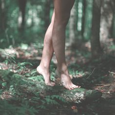 black and white photograph of woman's bare legs in the woods with trees behind her