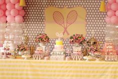 a table topped with lots of cakes and desserts covered in pink and yellow balloons