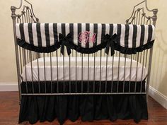 a black and white striped crib with monogrammed bedding