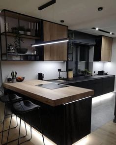 a modern kitchen with black cabinets and wooden counter tops is lit by recessed lighting