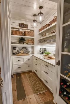 a kitchen with lots of white cabinets and wood flooring on the side walk in pantry