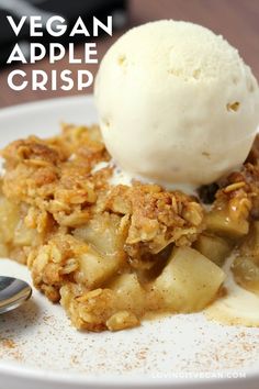 a white plate topped with an ice cream scoop and apple crumbled dessert next to a spoon