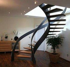 a spiral staircase in the middle of a room with wood flooring and white walls