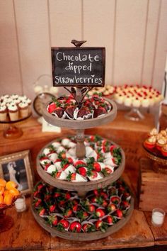 a table topped with three tiered trays filled with cupcakes and desserts