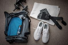 the contents of a duffel bag are laid out on the floor next to shoes