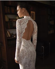 the back of a woman's wedding dress in front of a bookshelf