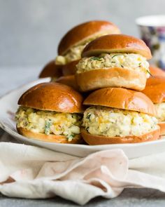 a plate filled with mini sandwiches on top of each other