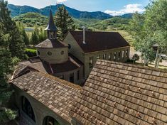 an aerial view of a church with mountains in the backgrouds and trees