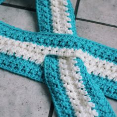 a crocheted blue and white tie laying on the ground next to a tile floor