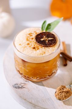 a drink with an orange slice on the top and cinnamon sprinkles around it