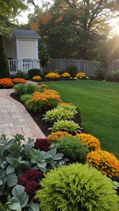 a garden with lots of green and yellow flowers in the grass next to a brick walkway