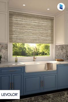 a kitchen with blue cabinets and a white sink in front of a window that has roman shades on it