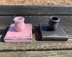 two small vases sitting on top of a wooden table next to each other,