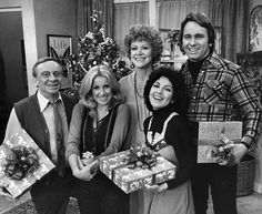 a group of people holding presents in front of a christmas tree