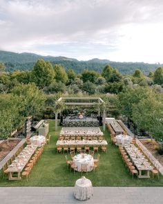 an outdoor wedding reception setup with tables and chairs set up in the middle of a field