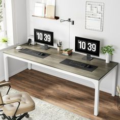 two computer monitors sitting on top of a wooden desk