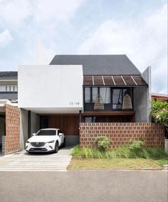 a white car parked in front of a house with an open garage door on the side