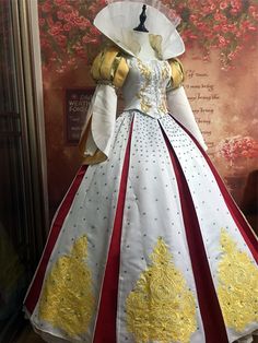 a white and red dress with gold trimmings on the chest, in front of a floral background