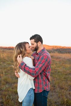 a man and woman kissing in an open field