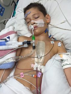 a young boy laying in a hospital bed with an oxygen tube attached to his head