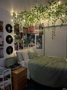 a dorm room with plants growing on the ceiling and vinyl records hanging from the wall