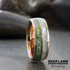 a wedding ring with green and white marble inlays on it's side