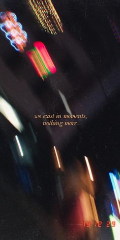 blurry photograph of colorful lights with text that reads, we exist in moments nothing more